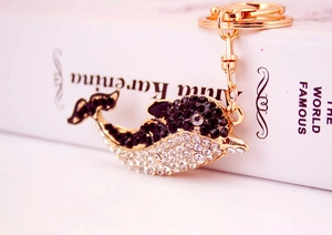 Macro shot of dolphin keychain featuring black and white rhinestones on golden metal base