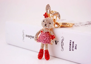 Close-up of cute rabbit keychain with red rhinestones and floral dress on a white book