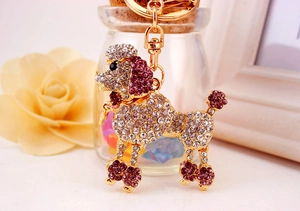 Detail of a gold-plated poodle keychain with white and purple rhinestones on a metal ring