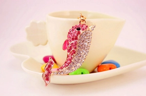 Detail of rose gold dolphin charm with pink and white rhinestones on a lifestyle background