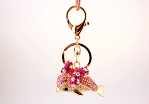 Detail of a sparkling dolphin keychain with pink rhinestones and a golden bow accent