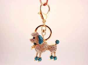 Detail of a gold poodle keychain inlaid with sparkling white and blue rhinestones
