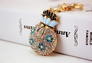 Detail of blue flower luck pouch keychain with crystals next to a book