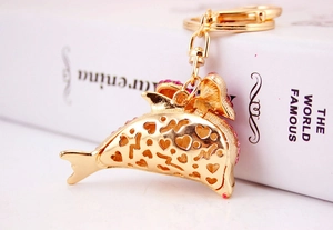 Macro shot of a pink rhinestone dolphin keychain with golden heart cutout patterns