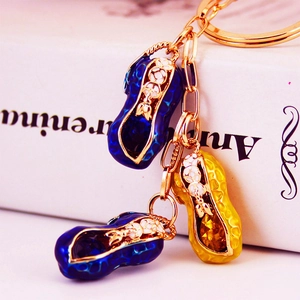 Peanut keychain with blue and gold enamel charms and inlaid crystals on white background