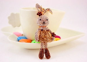 Detail of cute rabbit keychain with rhinestones leaning on white coffee cup