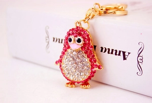 Close-up of pink and white crystal penguin keychain with golden metal ring and chain