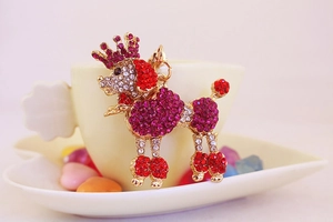 Close-up of a sparkling poodle keychain with rhinestones hanging on a cream ceramic cup