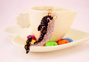 Macro detail of golden dolphin keychain featuring black and clear inlaid rhinestones