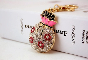 Close-up of money bag keychain with white rhinestones and pink enamel details
