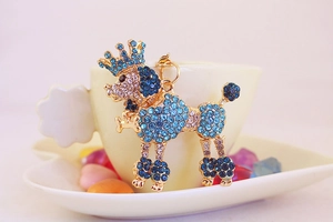 Detail of blue rhinestone poodle keychain with crown charm on a white ceramic plate
