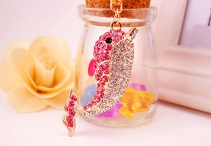 Detail of pink and white crystal dolphin keychain with golden plating for bags