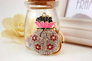 Detail of red and white floral rhinestone lucky bag keychain with pink enamel accent