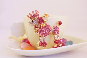 Macro shot of pink rhinestone poodle keychain with crown detail on a cream cup