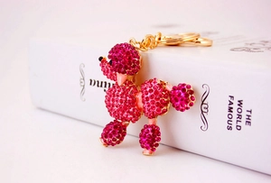 Detail of rose pink rhinestone poodle keychain with gold metal clasp on white books