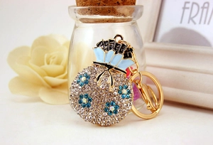 Detailed view of lucky bag keychain with blue crystals and floral enamel on gold metal