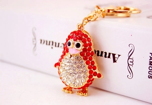 Macro detail of the penguin keychain featuring red and white rhinestones and gold lobster clasp