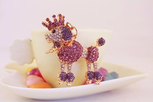 Close-up of golden poodle keychain with pink and purple rhinestones and crown