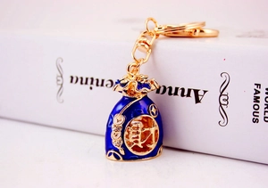 Macro detail of blue enamel lucky bag keychain with gold rhinestones and coin pattern