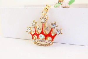 Macro shot of gold crown keychain with red enamel and sparkling rhinestones