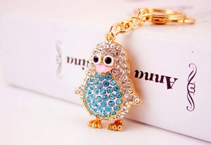 Close-up of golden penguin keychain featuring blue and clear rhinestones and lobster clasp