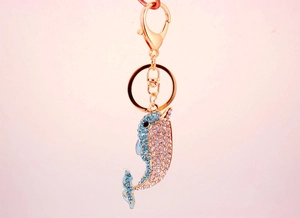 Detailed close-up of a rose gold dolphin keychain featuring blue and clear rhinestones