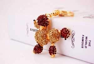 Detail of red and amber rhinestone poodle keychain with golden metal ring and spring clasp