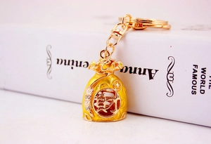 Detailed view of a golden Chinese lucky money bag keychain with red enamel and crystals