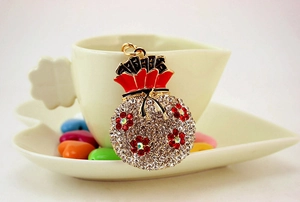 Detail of flower pattern money bag keychain with red enamel and rhinestones on a cup