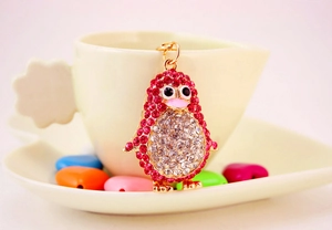Close-up of a sparkling rhinestone penguin keychain hanging on a yellow coffee cup