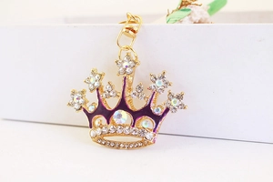 Detailed macro view of the gold crown keychain with crystal rhinestones and purple enamel