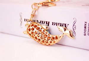 Close-up of golden dolphin keychain with blue rhinestones and hollow flower details