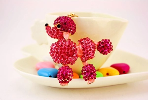 Close-up of rose red rhinestone poodle keychain hanging on a beige coffee cup