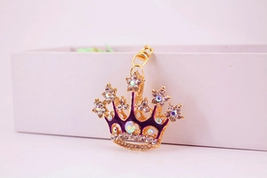 Detailed macro view of a gold crown keychain with purple enamel and crystal rhinestones