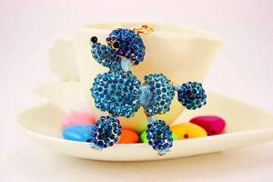 Detailed view of poodle keychain with blue rhinestones in a heart shaped ceramic dish