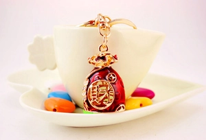 Detailed close-up of a red and gold Chinese lucky bag keychain on a ceramic cup edge