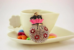 Macro shot of rhinestone money bag pendant with red floral patterns and pink enamel