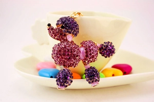 Macro shot of a purple rhinestone-encrusted poodle keychain displayed on a white tea saucer