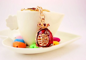 Detail of a red enamel lucky bag keychain with gold rhinestones on a coffee cup