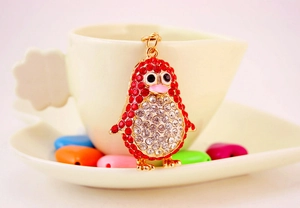 Detail of penguin keychain with red and white rhinestones hanging on a coffee cup