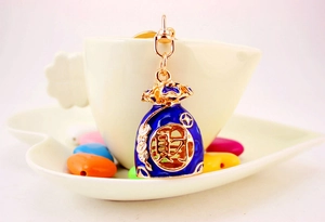 Detail of blue enamel lucky money bag keychain with crystal accents and golden finish