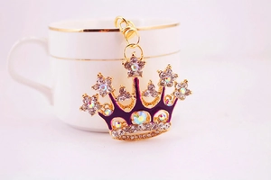 Detail view of purple enamel crown keychain with crystals on a white ceramic cup