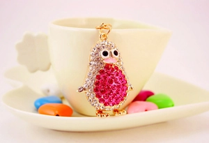 Detail of pink and white crystal encrusted penguin keychain on a creamy coffee cup