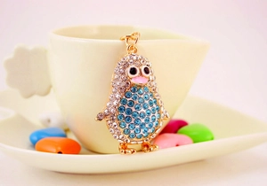 Detail of a sparkling crystal penguin keychain hanging on a cup with blue rhinestones