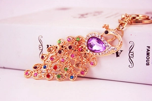 Close-up of golden peacock keychain with purple stones and colorful rhinestones