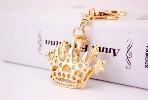 Detailed close-up of a hollow golden crown keychain with star and beaded metal accents