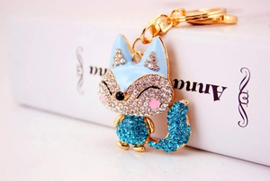 Close-up of a sparkling fox keychain with blue rhinestones on a gold-plated base