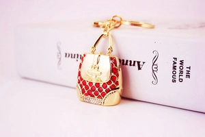 Detail of a red enamel handbag keychain with white rhinestones on a golden alloy base