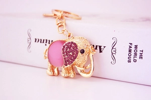 Detail of golden elephant keychain with pink cat eye stone and purple rhinestones