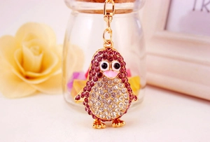 Detailed macro shot of a gold-toned cartoon penguin keychain set with purple rhinestones
